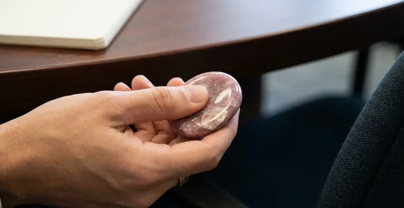 Mano che tiene una worry stone di lepidolite rosa durante una riunione